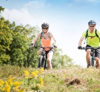 Couple mountain biking on trail during summer